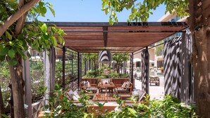 An outdoor patio with wooden furniture, a pergola, and lush greenery. - Radisson Blu Hotel, Marrakech Carré Eden (Marrakech)
