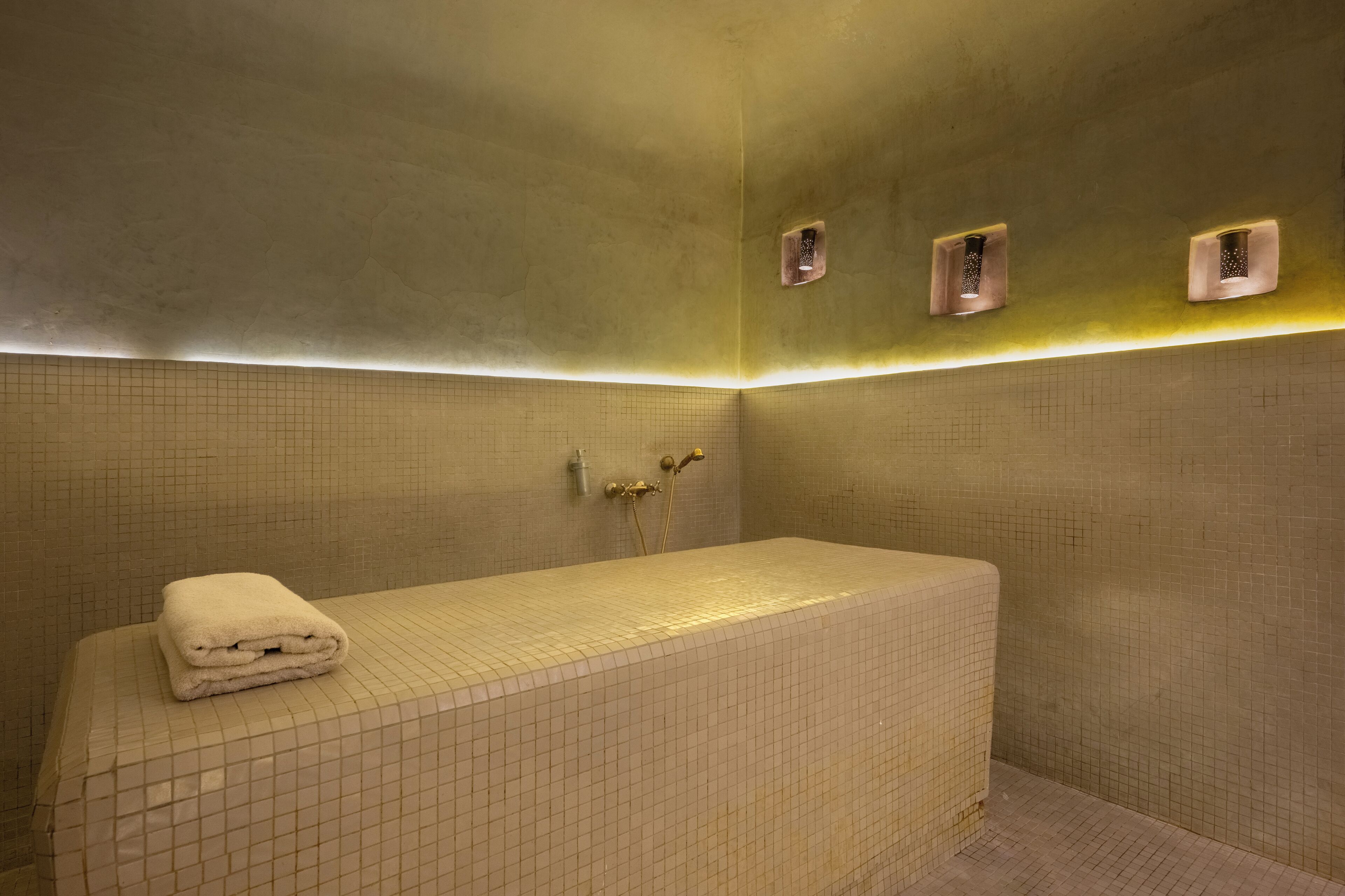 Un baño con una bañera grande, una toalla en el borde y un revestimiento de pared con diseño de cuadrícula.