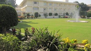 A large, multi-story building with a well-maintained lawn and a fountain in the center. - Hotel Ritz Plaza (Amritsar)