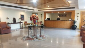 A spacious lobby with a reception desk, seating area, and a decorative floral arrangement. - Hotel Ritz Plaza (Amritsar)