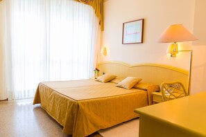 Une chambre d’hôtel avec un lit, une table de chevet, une lampe et une chaise.