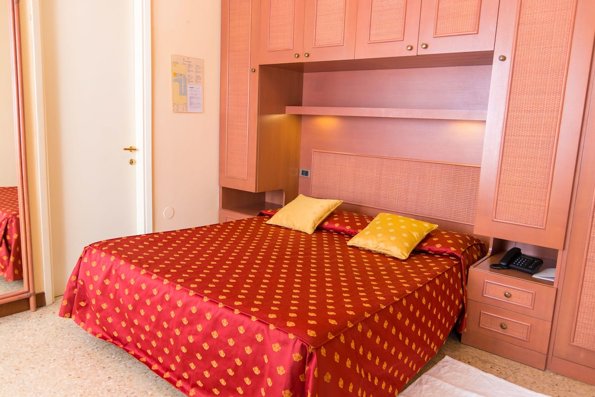 Ein Schlafzimmer mit Bett, zwei Kissen, einem Nachttisch und einem Kleiderschrank.