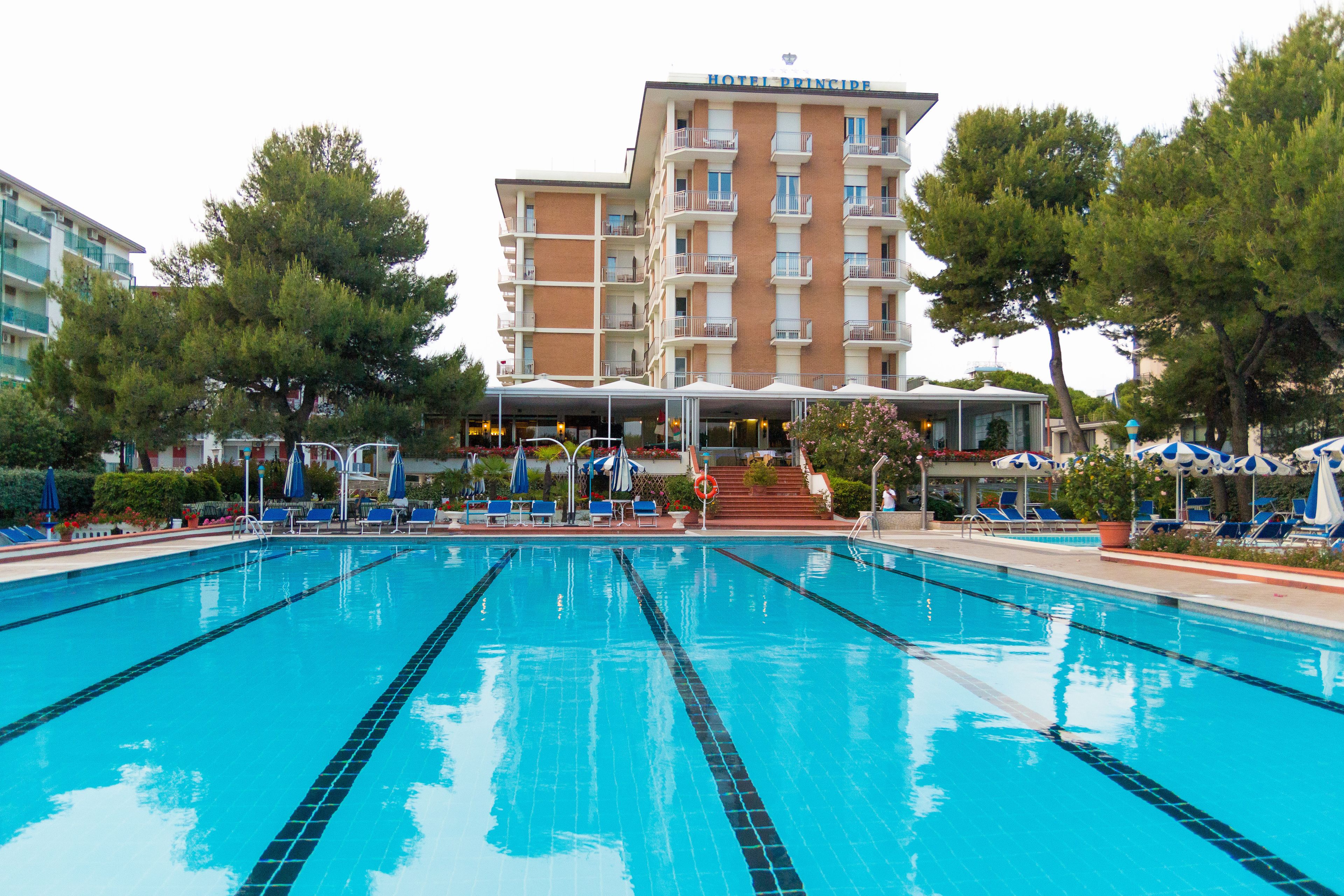 Un hôtel doté d’une piscine, de chaises longues et d’un espace abrité avec des parasols.