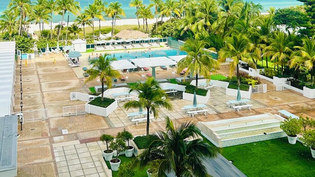 Un resort con zona de piscina, palmeras y vista al océano.