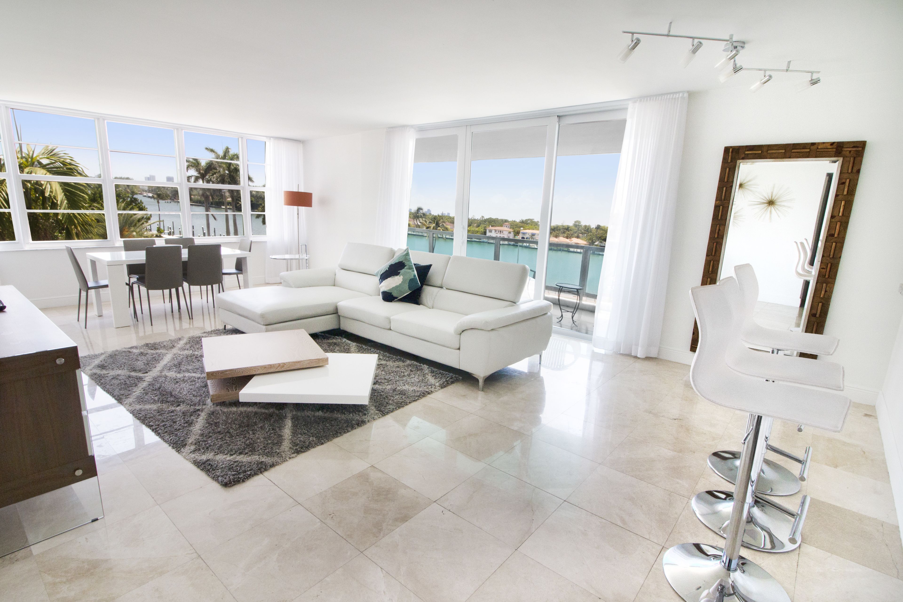 Una sala de estar moderna con un sofá blanco, una mesa de centro y un comedor con sillas y una mesa.