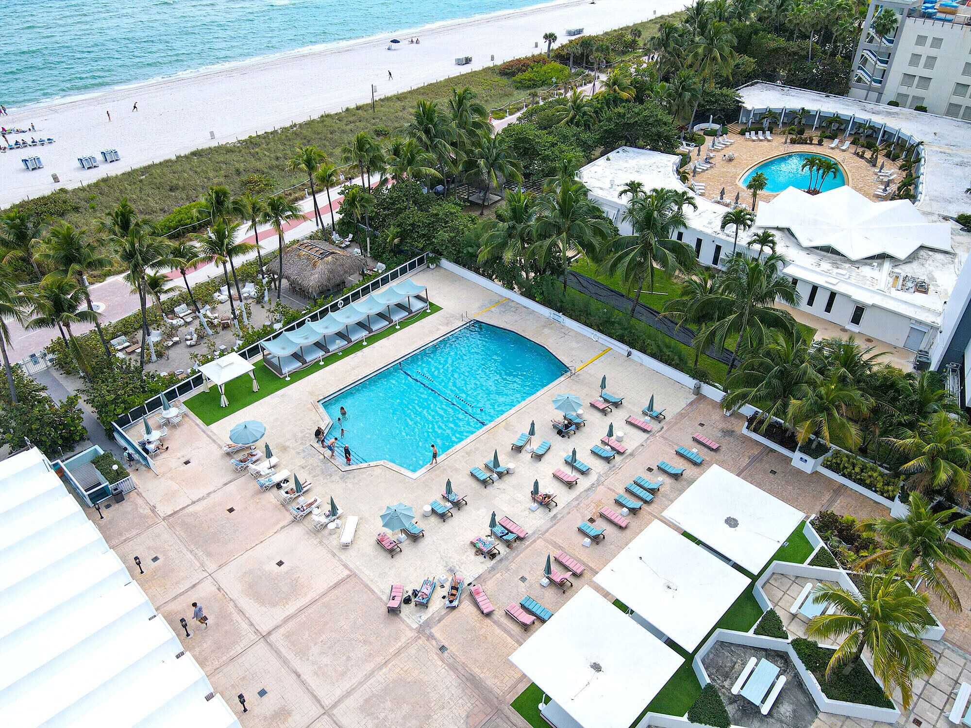 Een resort met een groot zwembad, ligbedden en een strand.