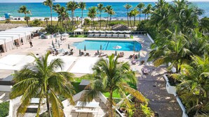 Un resort con piscina, playa y palmeras.