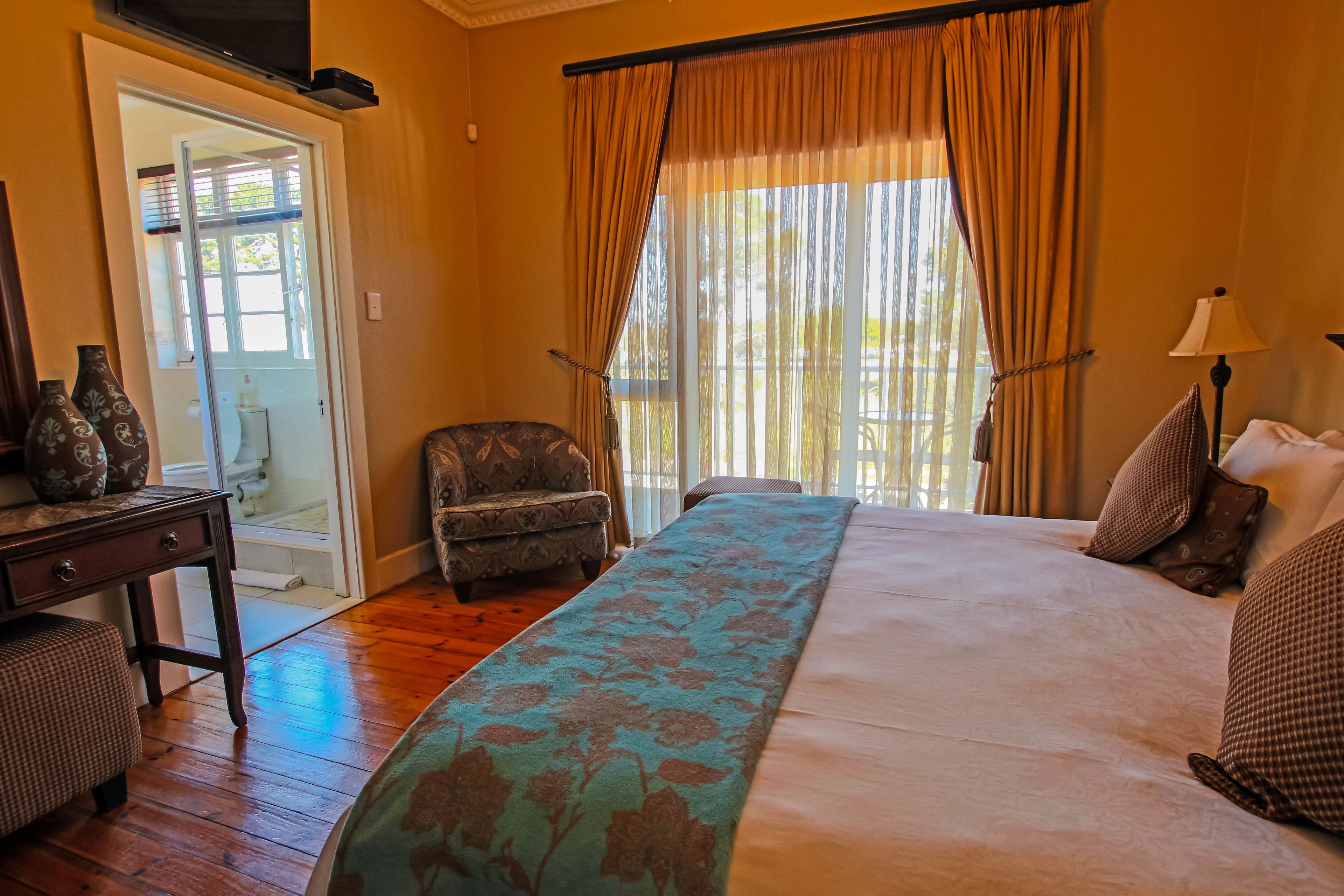 A bedroom with a bed, a chair, a nightstand, and a window with curtains.