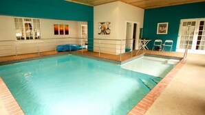 An indoor swimming pool with a clear water surface, surrounded by a white pool deck and a blue tiled border. - A&A Guesthouse (Gqeberha (Port Elizabeth))