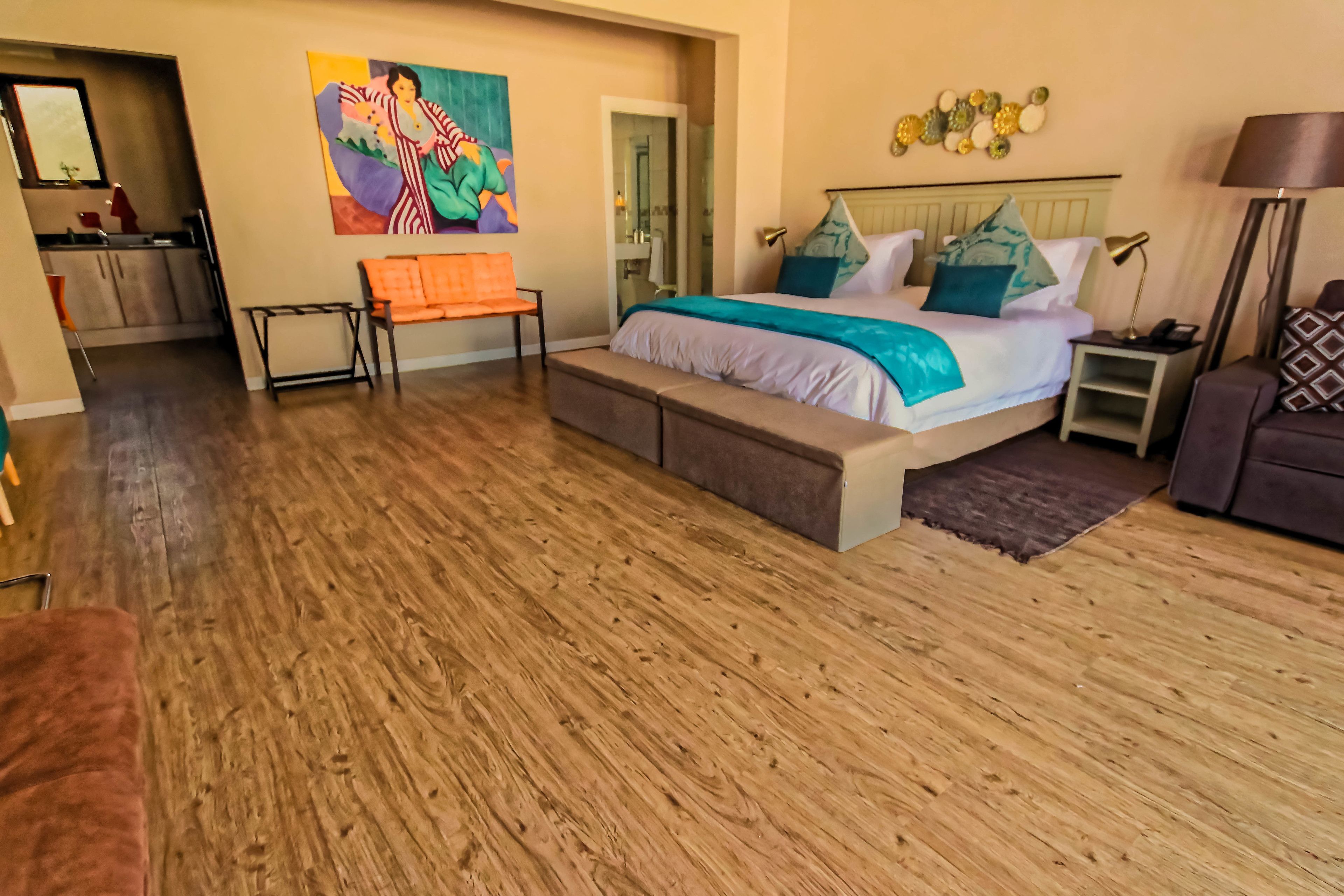 A spacious bedroom with a large bed, a bench, a desk, and a chair.