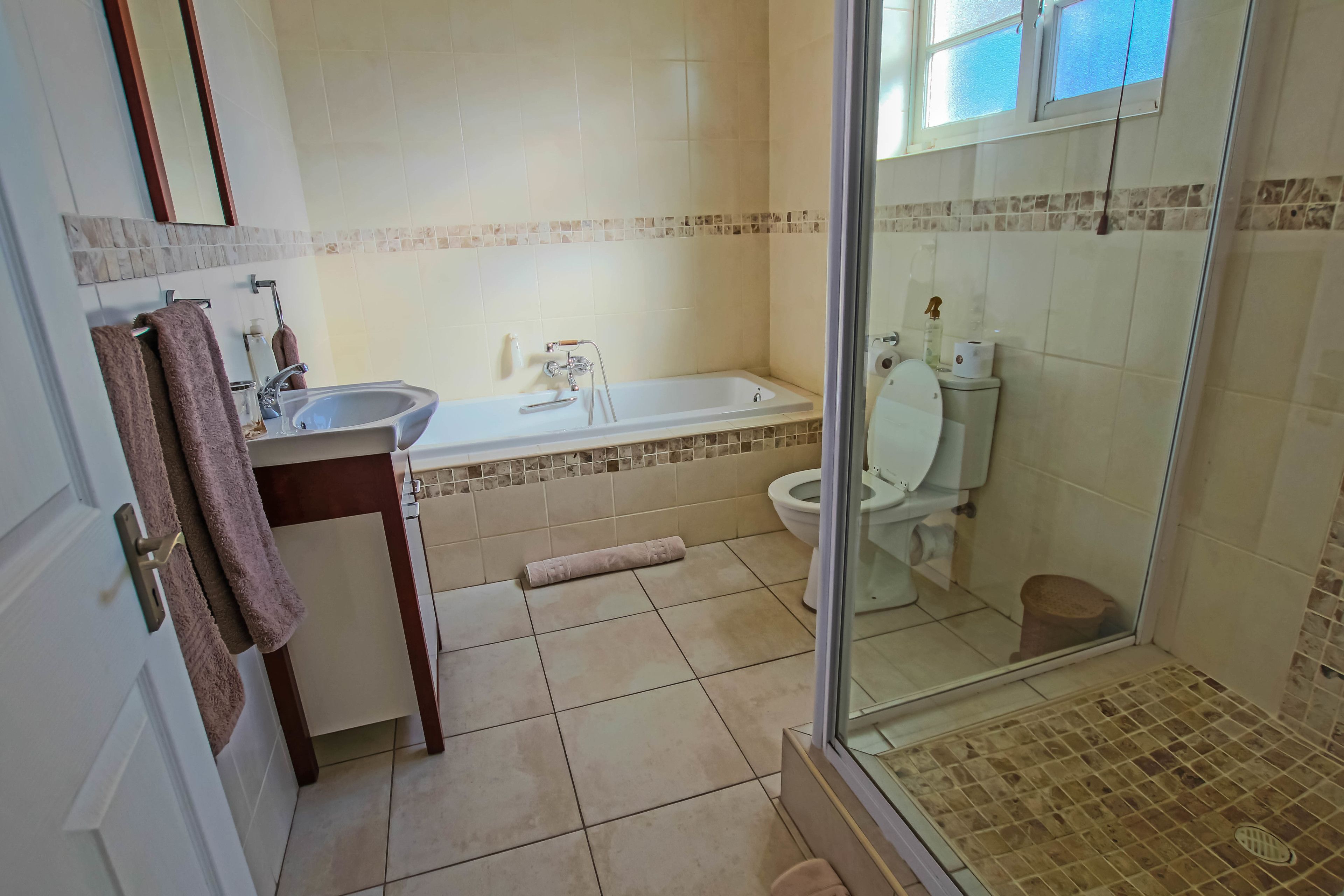 A bathroom with a bathtub, sink, toilet, and a glass shower enclosure.