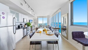 A modern kitchen with a dining area, large windows, and a view of the ocean. - Dharma Home Suites Miami at Monte Carlo (Miami Beach)