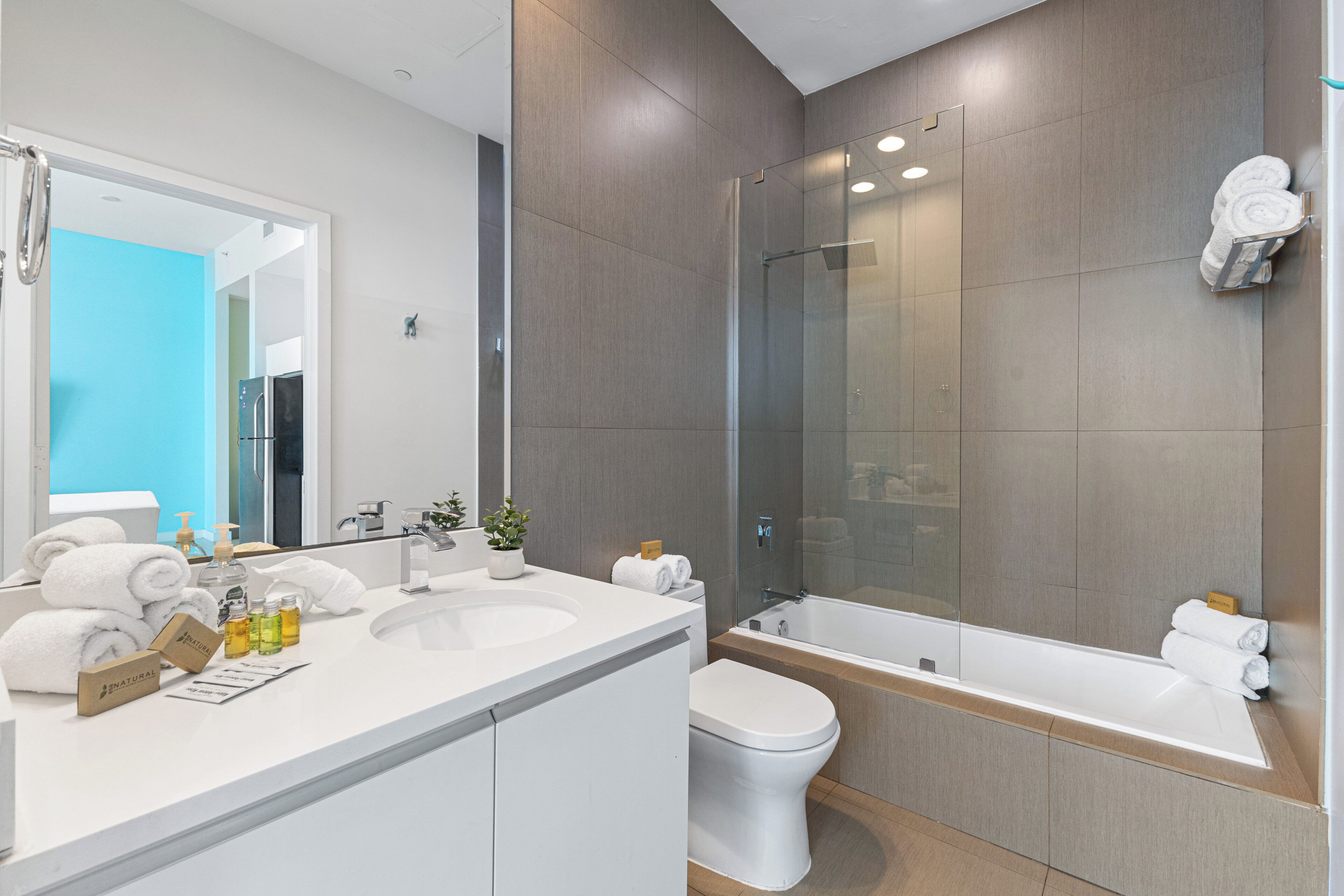A modern bathroom with a large mirror, a bathtub, a toilet, and a shower area.