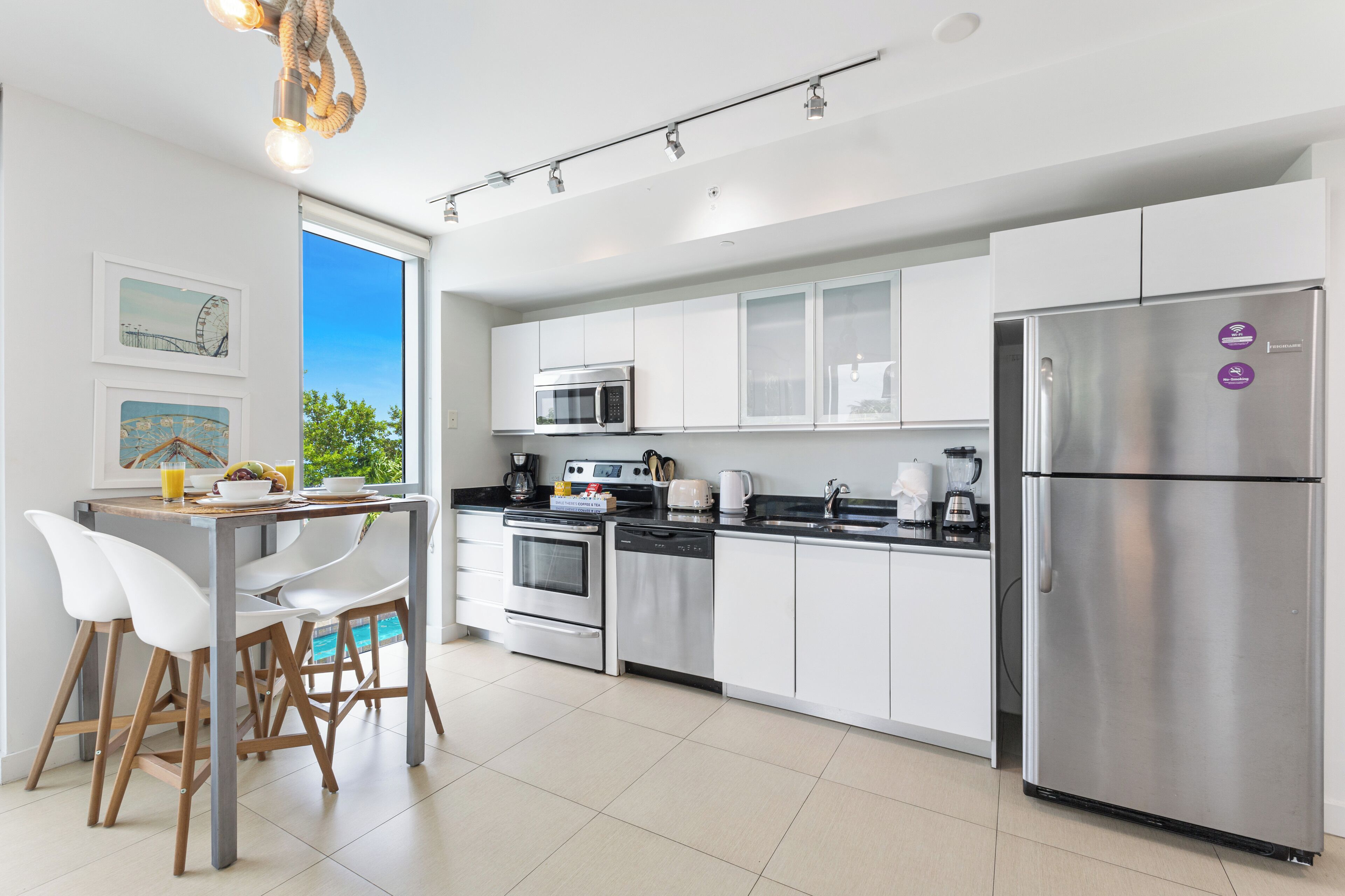 A modern kitchen with white cabinets, stainless steel appliances, and a dining area with white chairs.