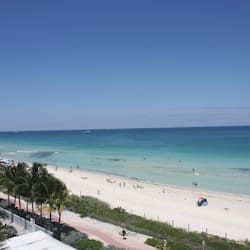 Na praia, areia branca, espreguiçadeiras, guarda-sóis