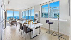 A modern kitchen with a dining area, large windows, and a view of the ocean. - Dharma Home Suites Miami at Monte Carlo (Miami Beach)