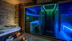 Ein Wellnessbereich mit Whirlpool, Glastüren und stimmungsvoller Beleuchtung.
