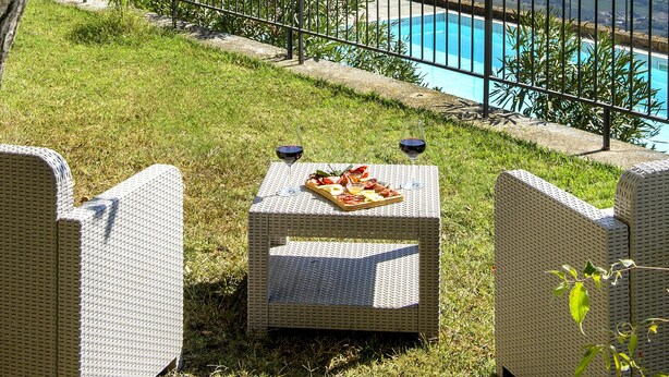 Ein Poolbereich mit Korbmöbeln und Blick aufs Meer.