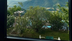 Aussicht aus einem Fenster auf eine gebirgige Landschaft, bewölkter Himmel.