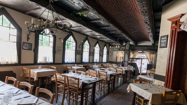 A restaurant with multiple tables and chairs, large windows, and a wooden ceiling. - Hotel L'Approdo (Cesenatico)