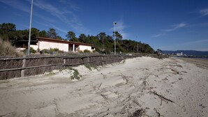 A beach with a wooden fence, a building with a red roof, and street lamps. - Le Dune (Follonica)