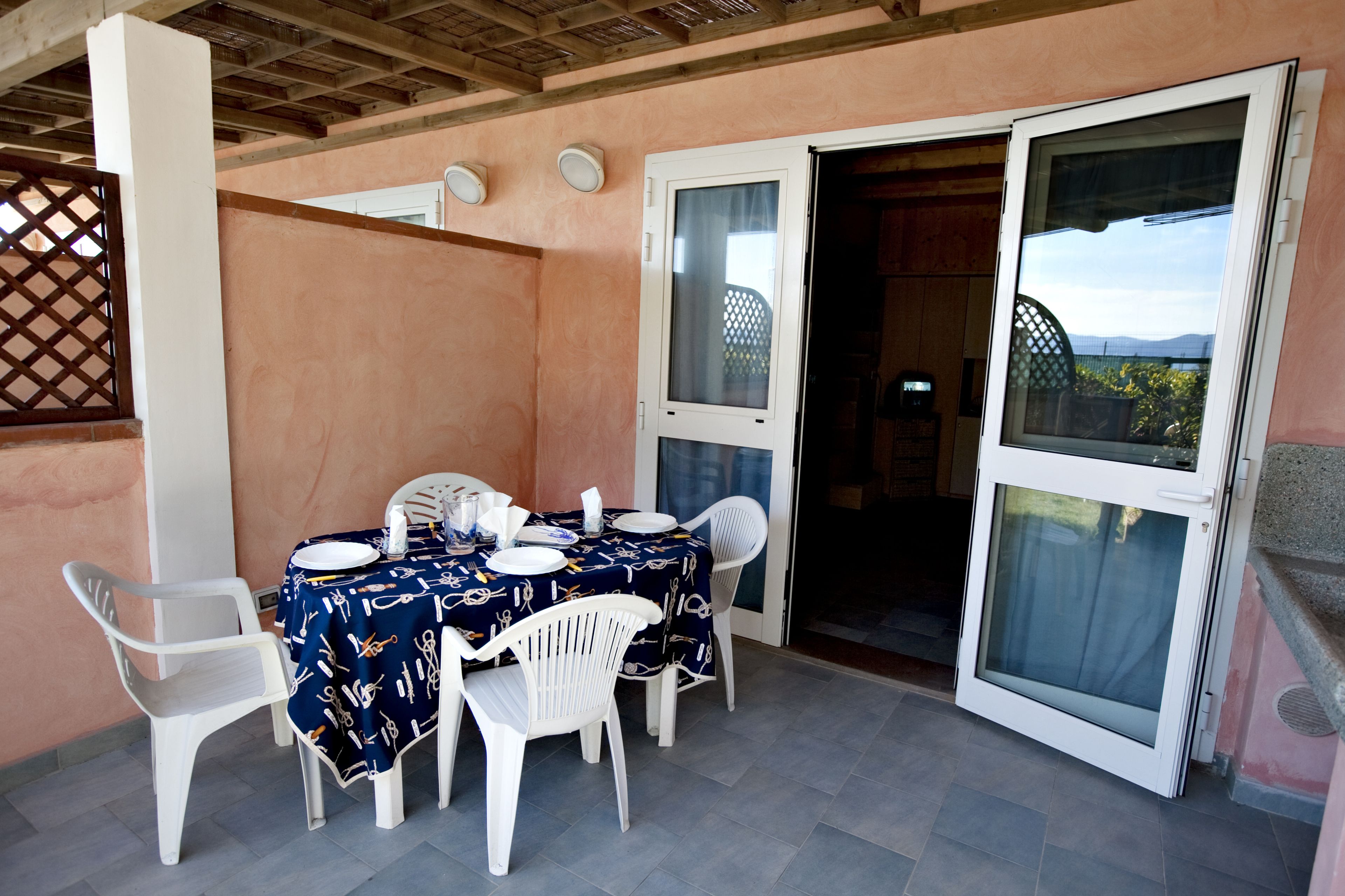 A dining area with a table set for four, white chairs, and a tablecloth with a nautical pattern.