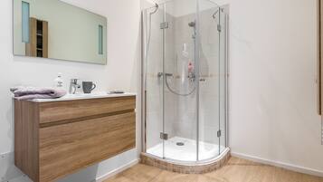 Une salle de bain moderne avec un meuble-lavabo en bois, une cabine de douche en verre et un grand miroir.