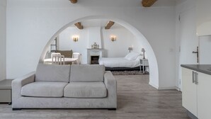 Ein modernes Interieur mit einer Couch, einem Esstisch mit Stühlen, einem Bett und einer Küchenzeile.