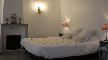 A bedroom with a large bed, a fireplace, and two bedside lamps.