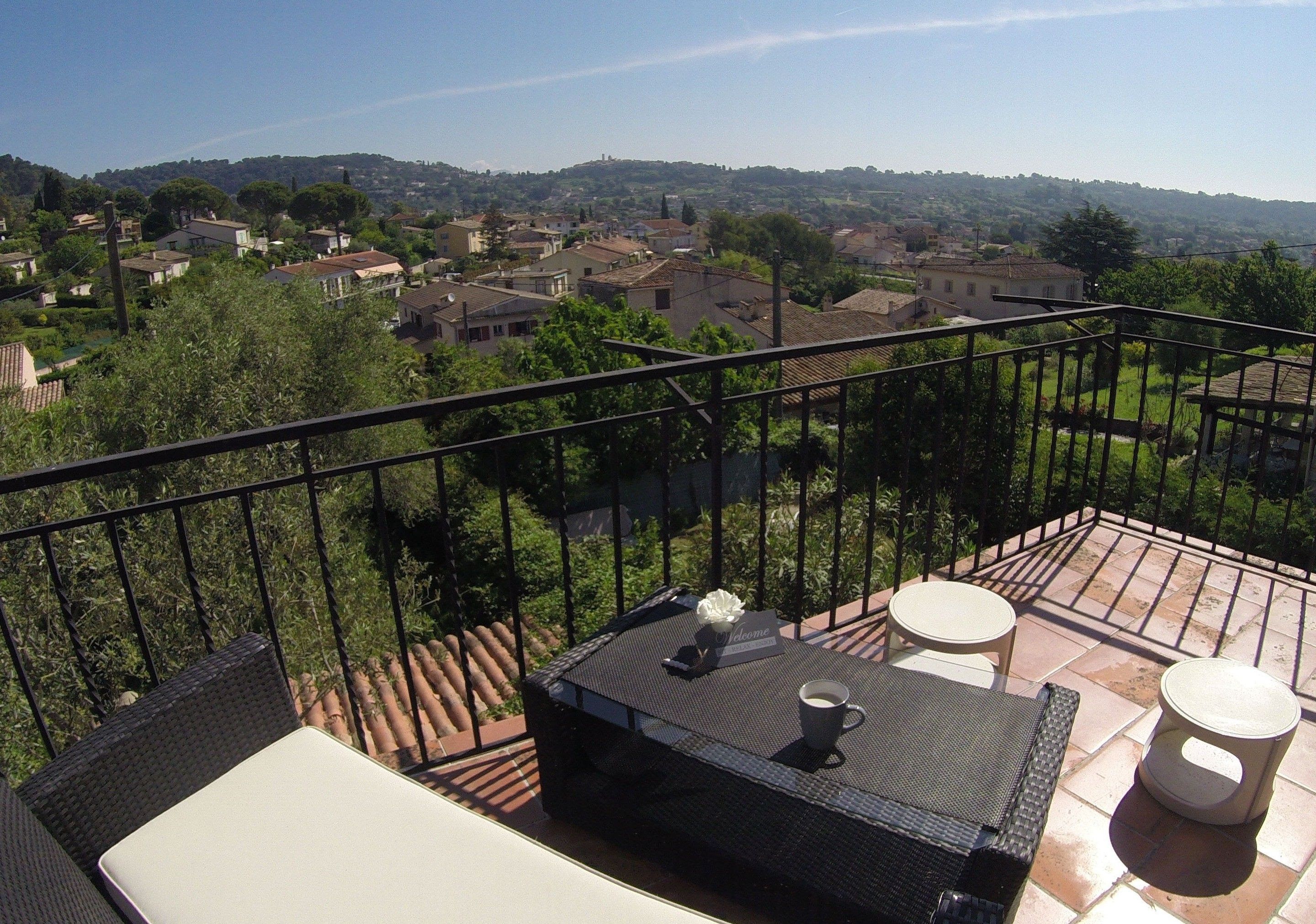 A balcony with wicker furniture, a table, and a view of a residential area.