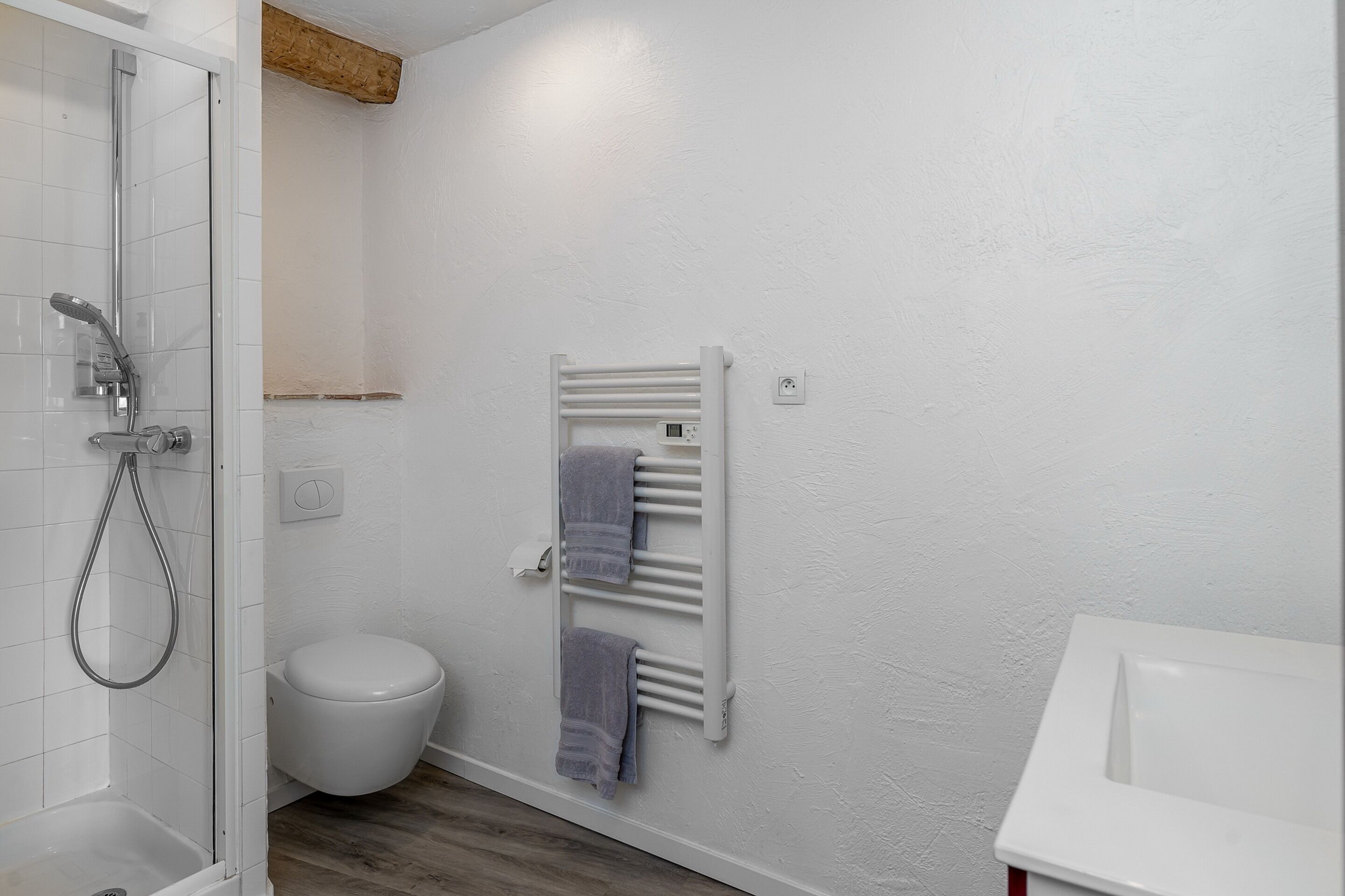 A bathroom with a shower, toilet, and towel rack.