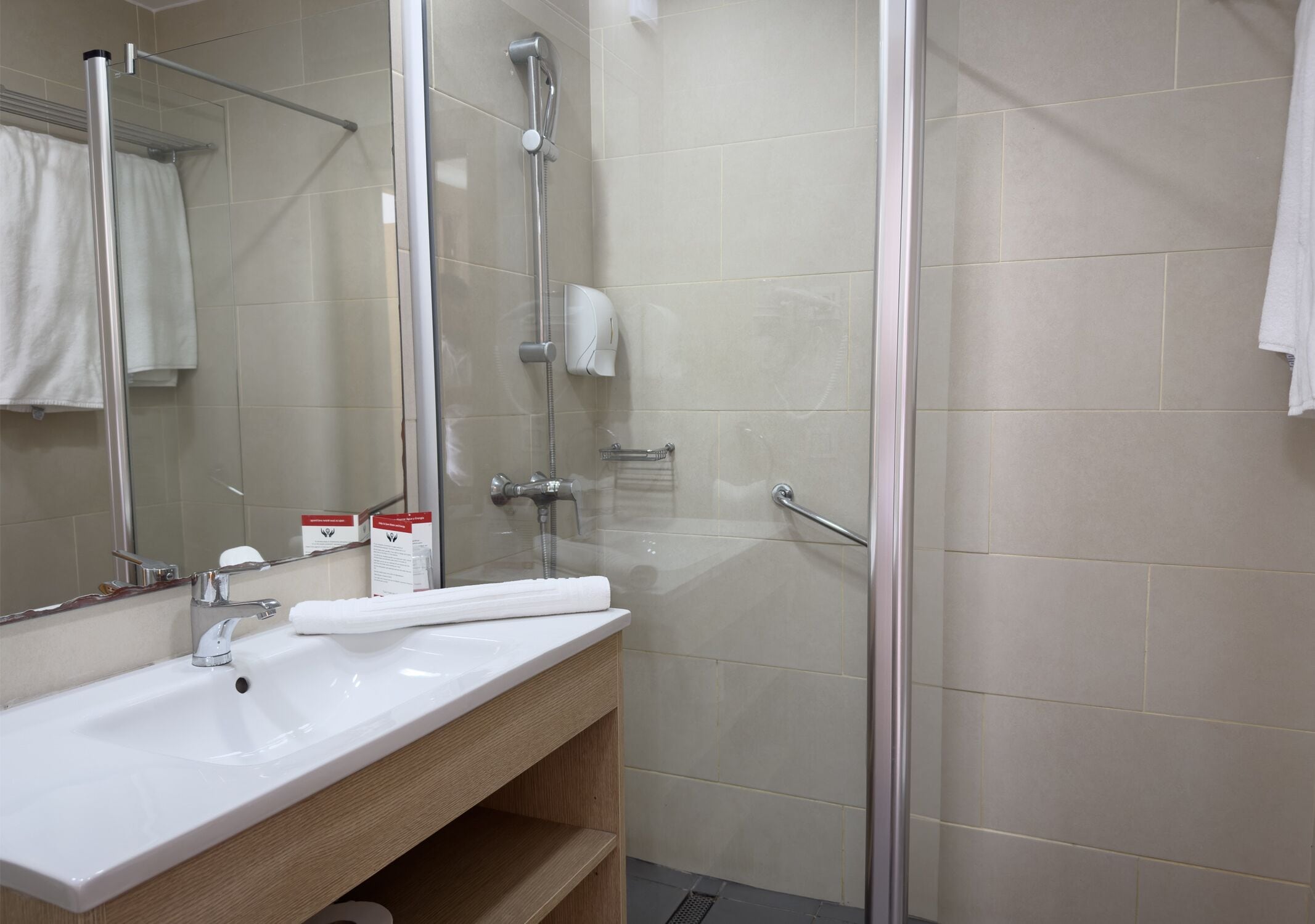 A bathroom with a white sink, mirror, and glass shower enclosure.