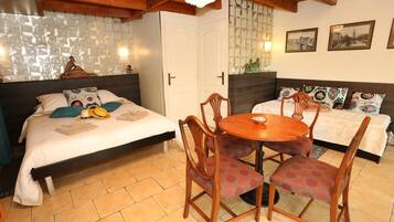 A cozy room with two beds, a wooden dining table, and a tiled floor.