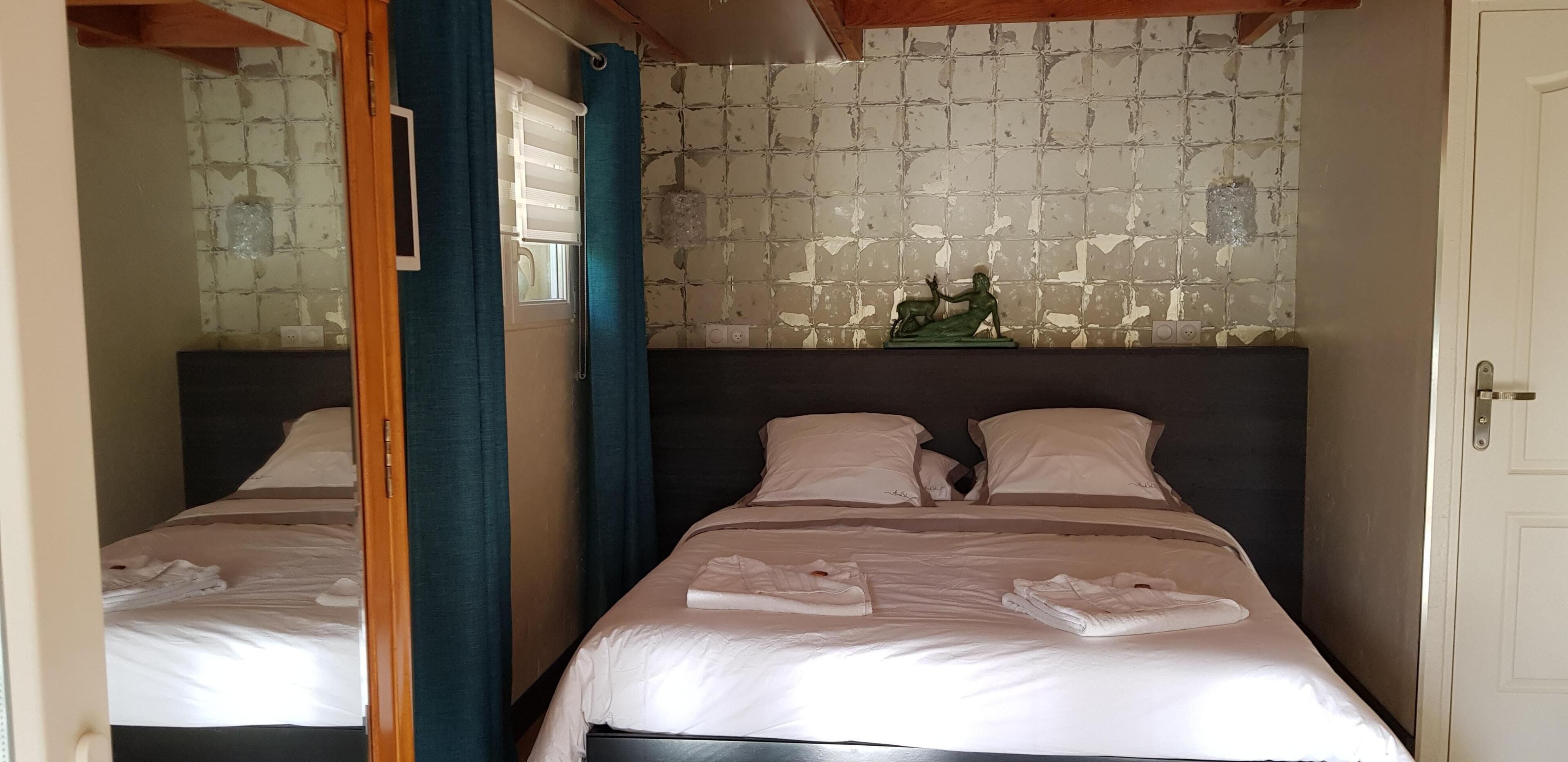 A hotel room with two beds, a decorative wall piece, and a wooden ceiling beam.