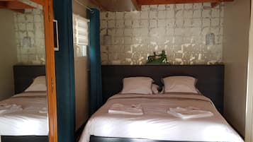 A hotel room with two beds, a decorative wall piece, and a wooden ceiling beam.