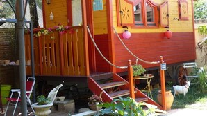 Une maison en bois aux couleurs vives, dotée d’un porche, de quelques marches et d’un petit jardin.