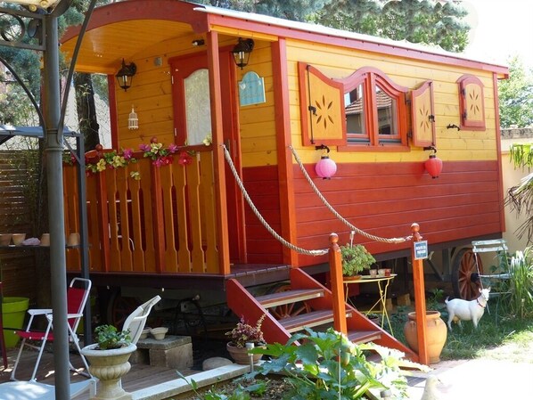 A colorful wooden house with a porch, steps, and a small garden area.