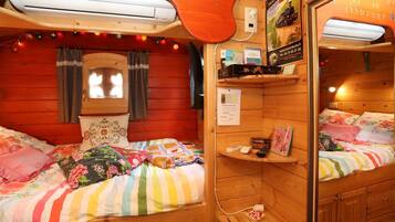 Ein gemütliches Blockhauszimmer mit zwei Betten, einem kleinen Fenster und Holzvertäfelung.