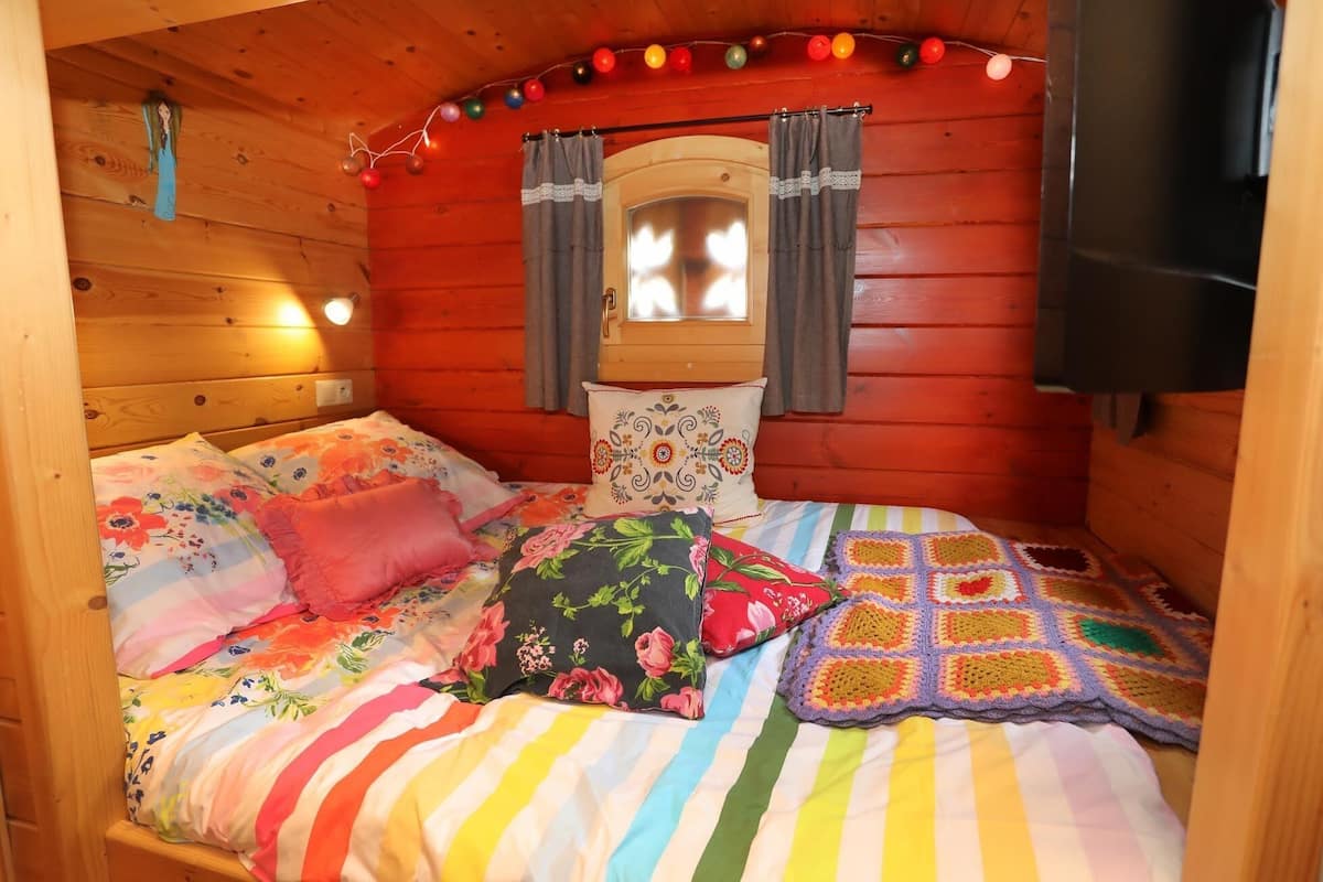 A cozy wooden cabin bedroom with a bed, pillows, and a crochet blanket.