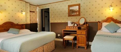 A room with two beds, a wooden desk, a chair, and a mirror.