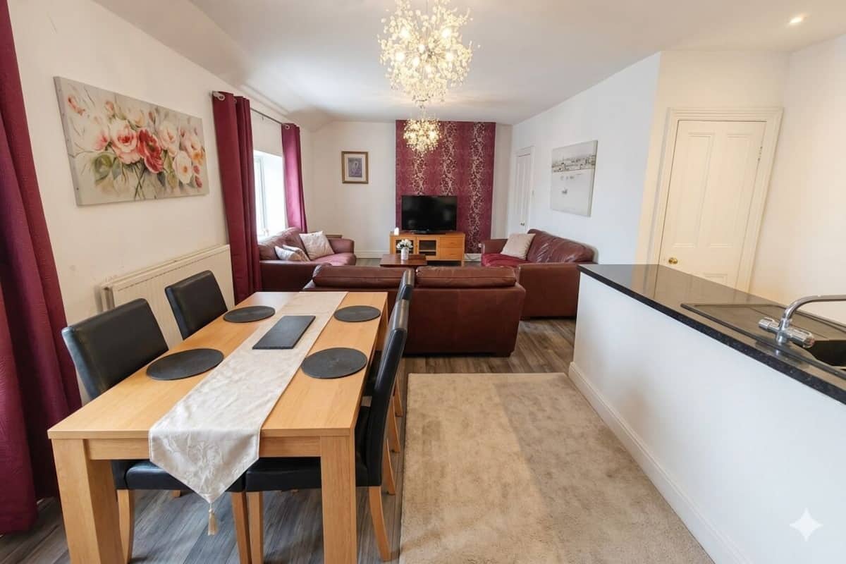 A modern kitchen with a dining area, a sofa set, and a TV.
