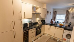 A modern kitchen with built-in appliances, a microwave, and a sink. - The Senarth (Llandudno)