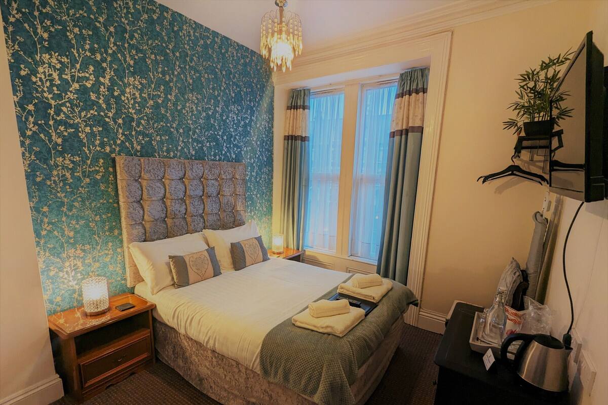 A neatly made bed with a tufted headboard, a bedside lamp, and a small nightstand.