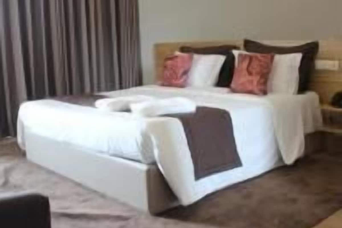 A hotel room with a large bed, a nightstand, and a curtain.