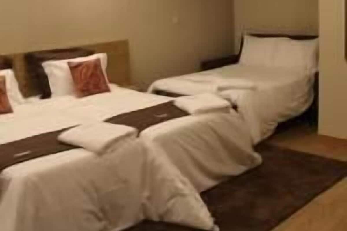 A hotel room with two beds, a headboard, and a brown rug.