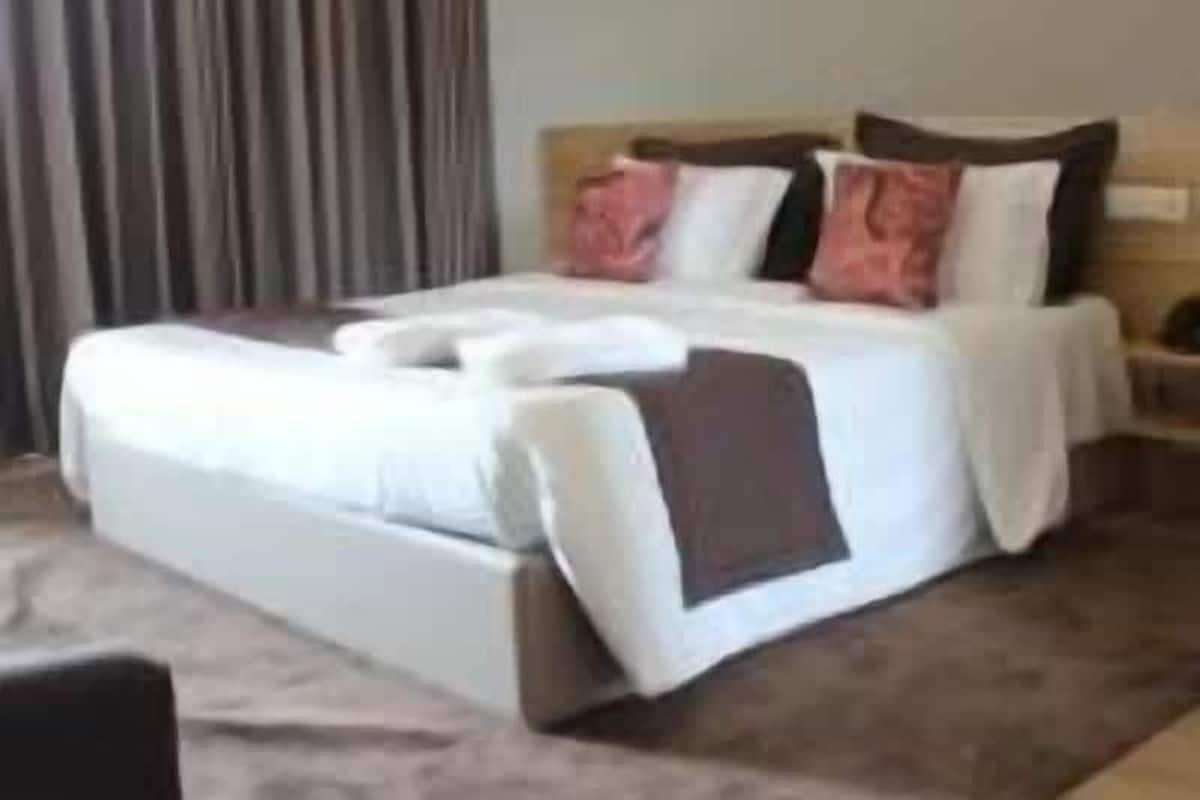 A hotel room with a large bed, a nightstand, and a window with curtains.