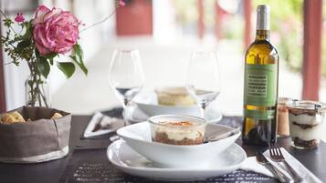 A table set with a dessert, wine, and a vase with a flower.