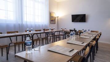 A conference room with long tables, chairs, water bottles, and documents.