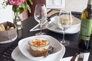 A dining table with a bottle of wine, a glass of water, a glass of white wine, a dessert in a glass, and a bowl of bread. - Hôtel Balea Guéthary (Guethary)