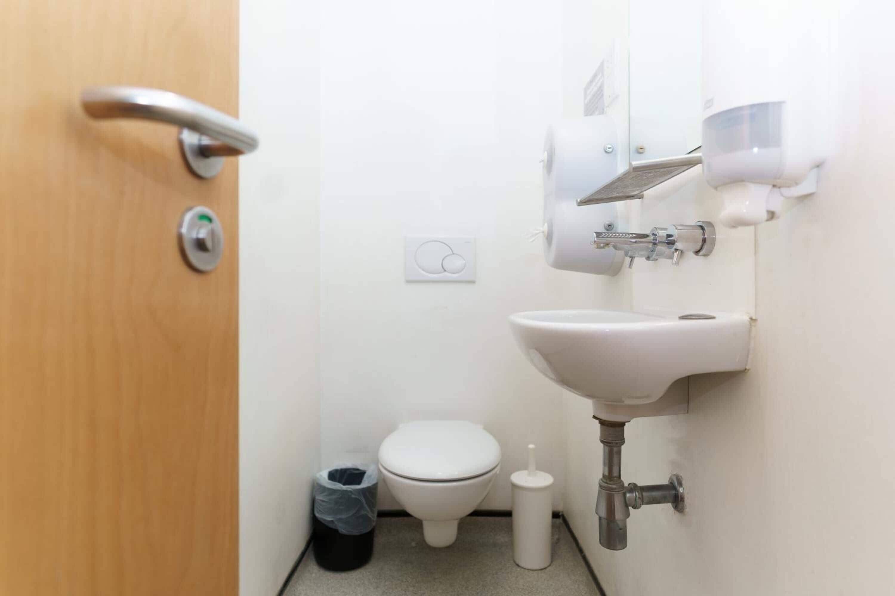 A small, clean bathroom with a toilet, sink, and hand dryer.
